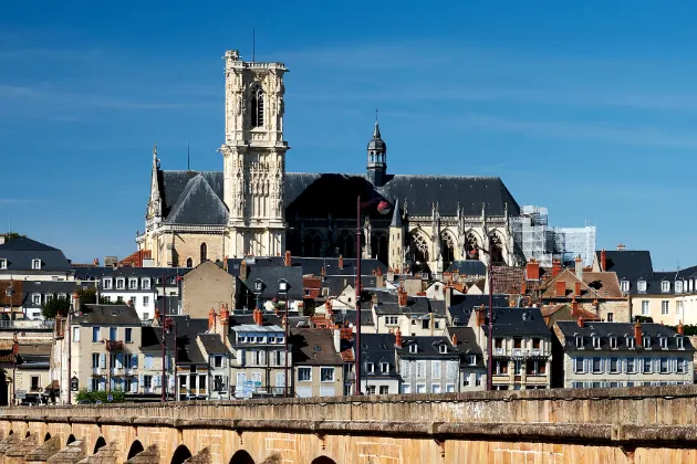 Imponente Catedral de Nevers com sua torre distinta dominando a paisagem urbana, exibindo a beleza da arquitetura gótica francesa.