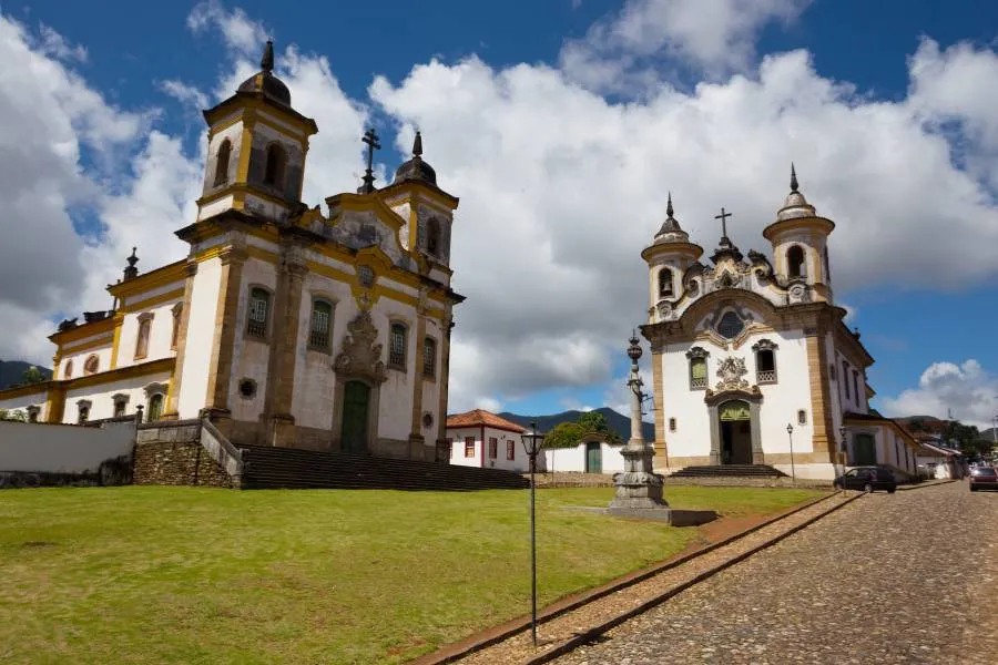 Igreja barroca em Mariana, Minas Gerais, com gramado e rua de pedra.