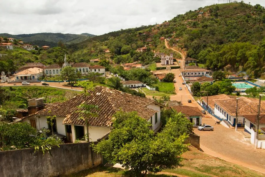 Paisagem urbana histórica de Serro, Minas Gerais, com casario colonial, igrejas e montanhas verdejantes ao redor.