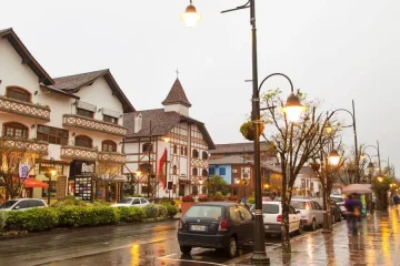 Rua com arquitetura europeia, carros estacionados e iluminação pública em Gramado