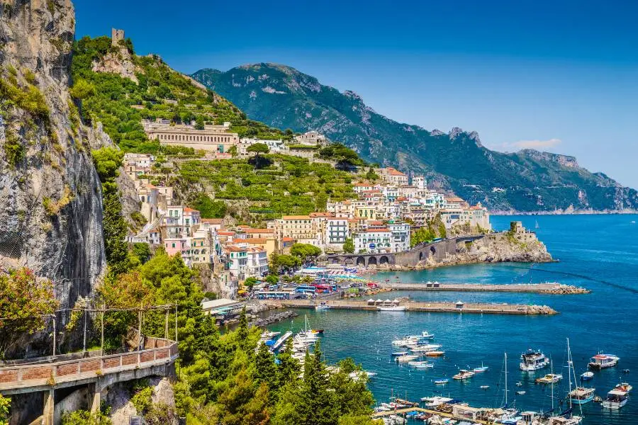 Vista panorâmica da cidade colorida de Amalfi, na costa da Itália, com mar azul e montanhas.