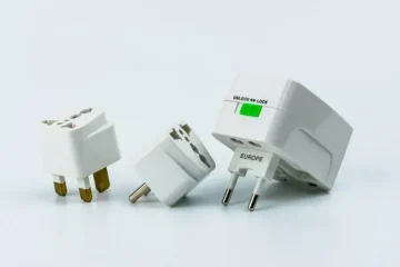 adaptadores de energia brancos, incluindo um adaptador universal para tomadas europeias.