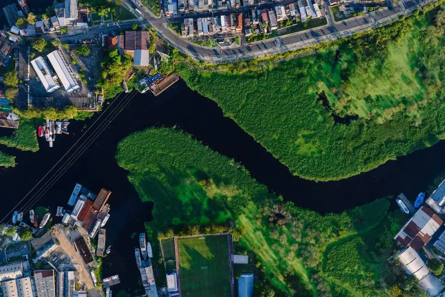 Vista aérea de canal sinuoso, na Amazônia, com construções e barcos.