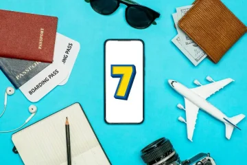 Smartphone com o número 7 cercado por itens de viagem como passaportes, dinheiro e avião.